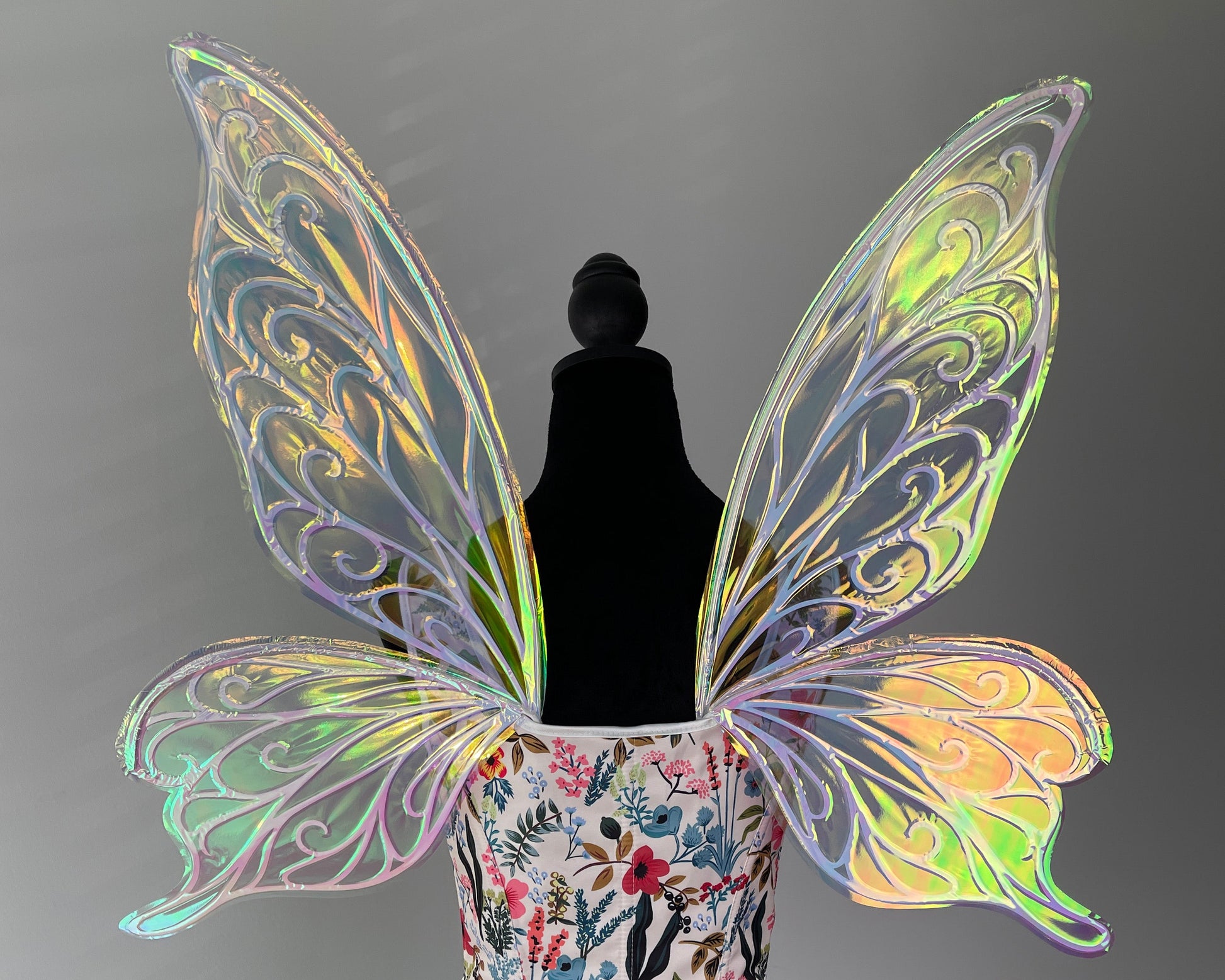Butterfly wings on a mannequin with a floral-patterned top against a gray background