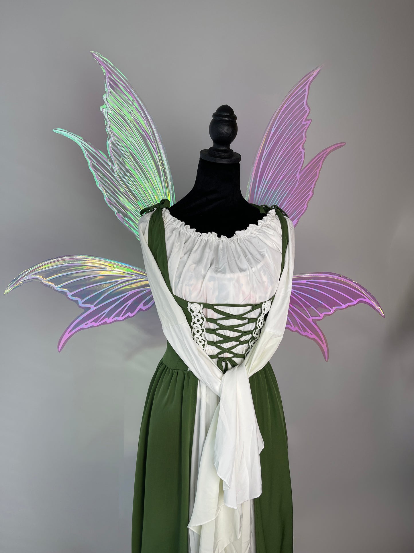 Mannequin wearing a green dress with white lace top and fairy wings on a gray background