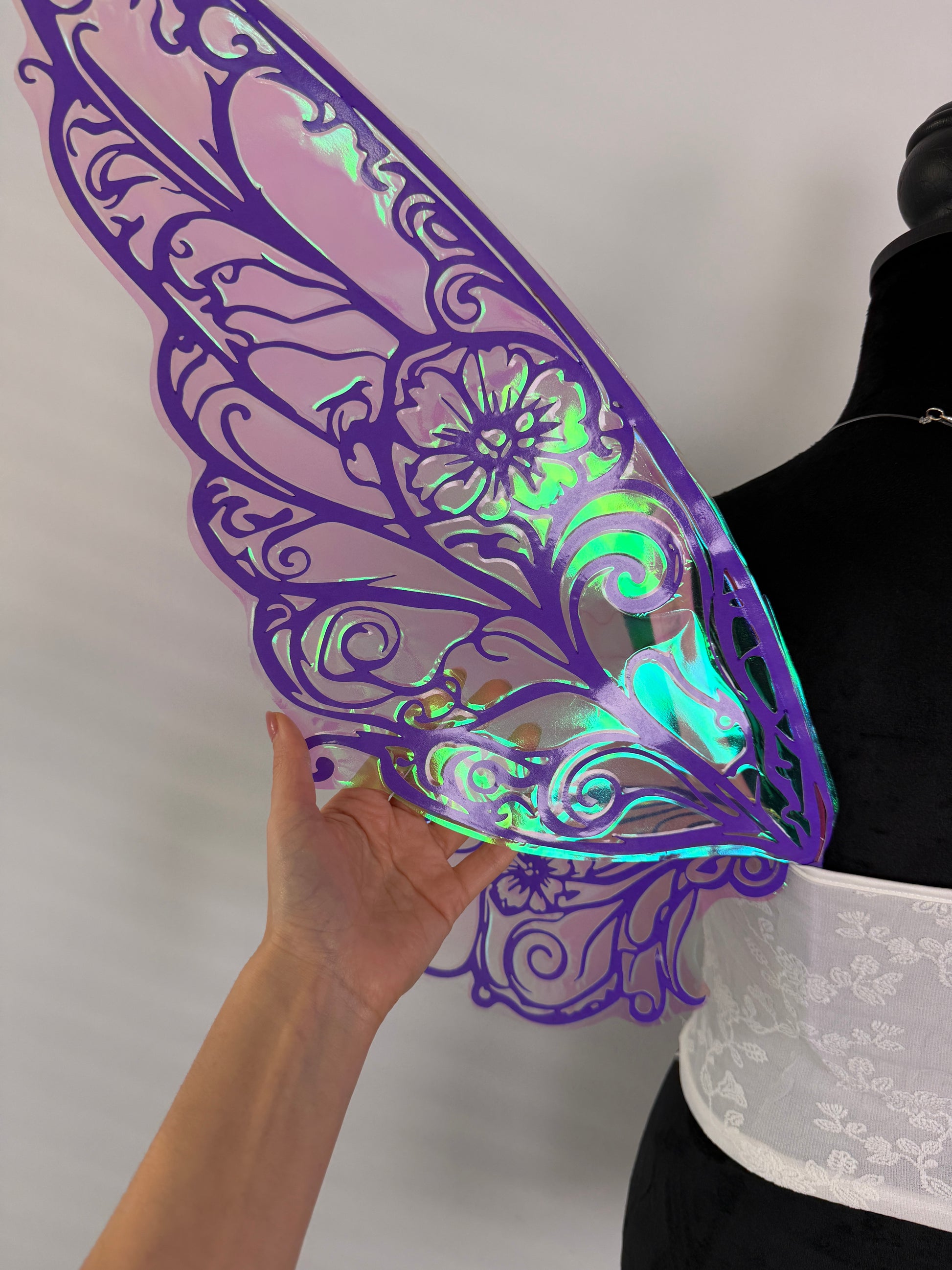 Decorative purple wing held by a hand on a white background