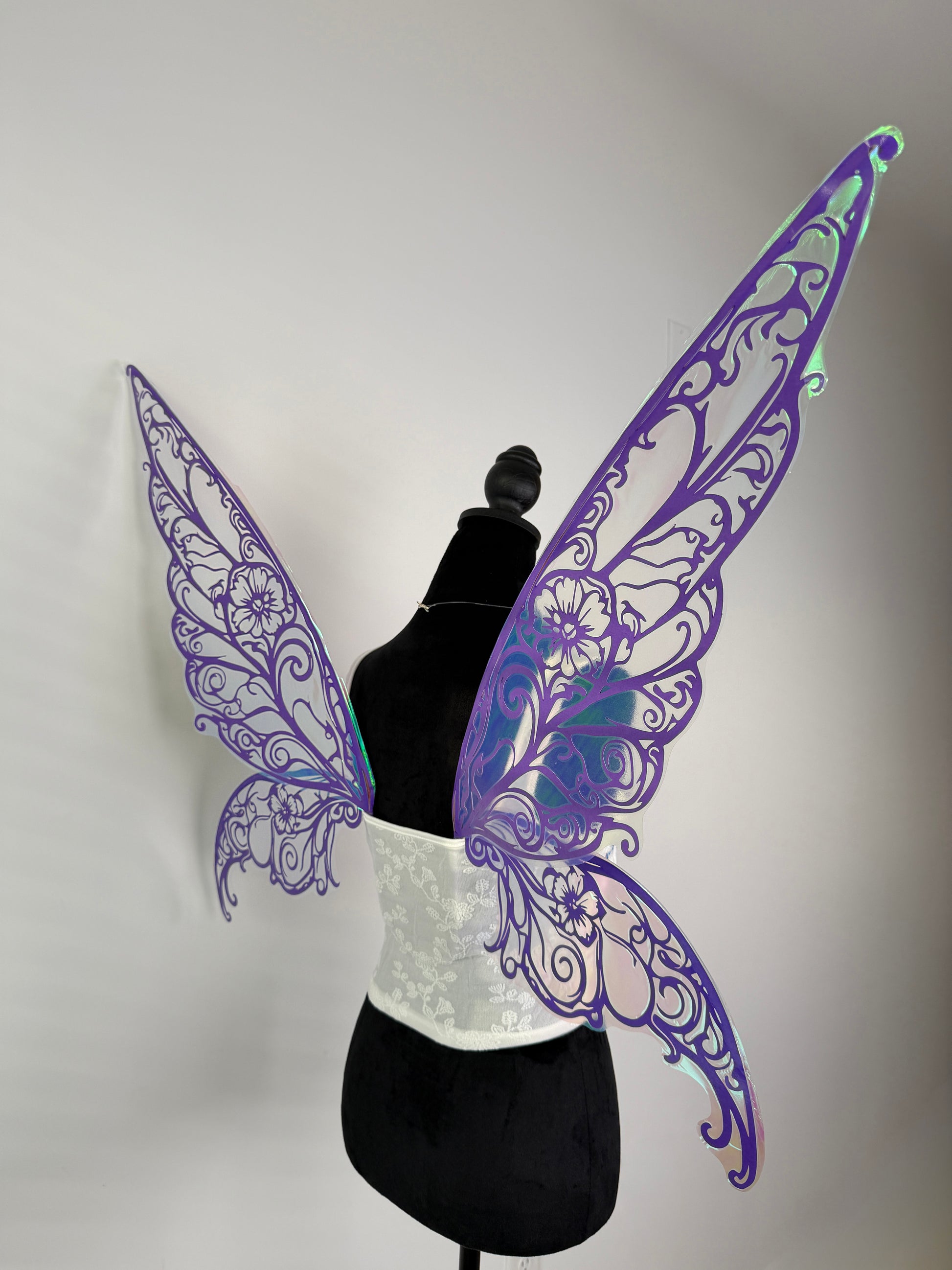 Purple butterfly wings on a mannequin against a gray background side view
