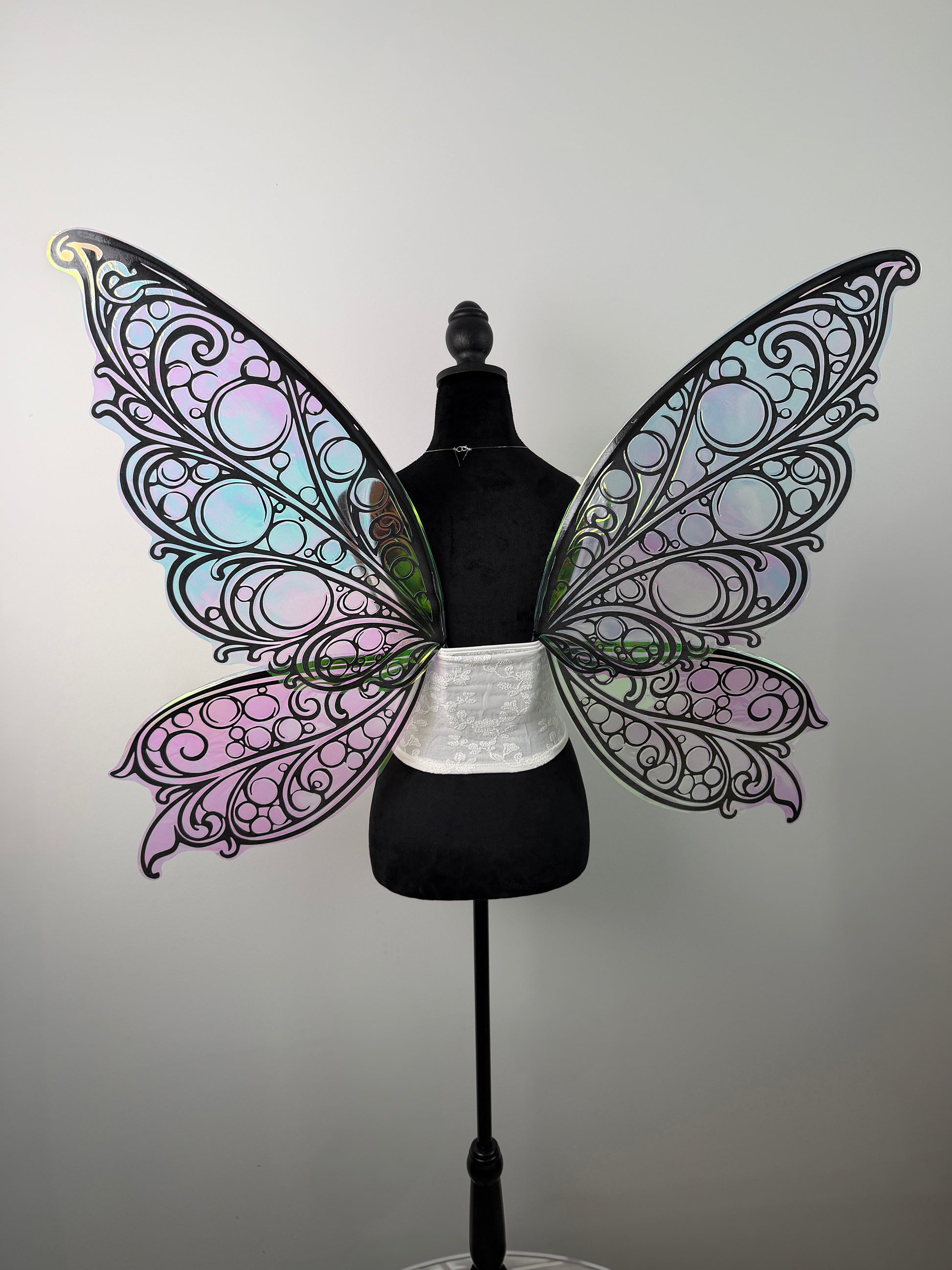 Butterfly wings with intricate designs on a mannequin against a plain background