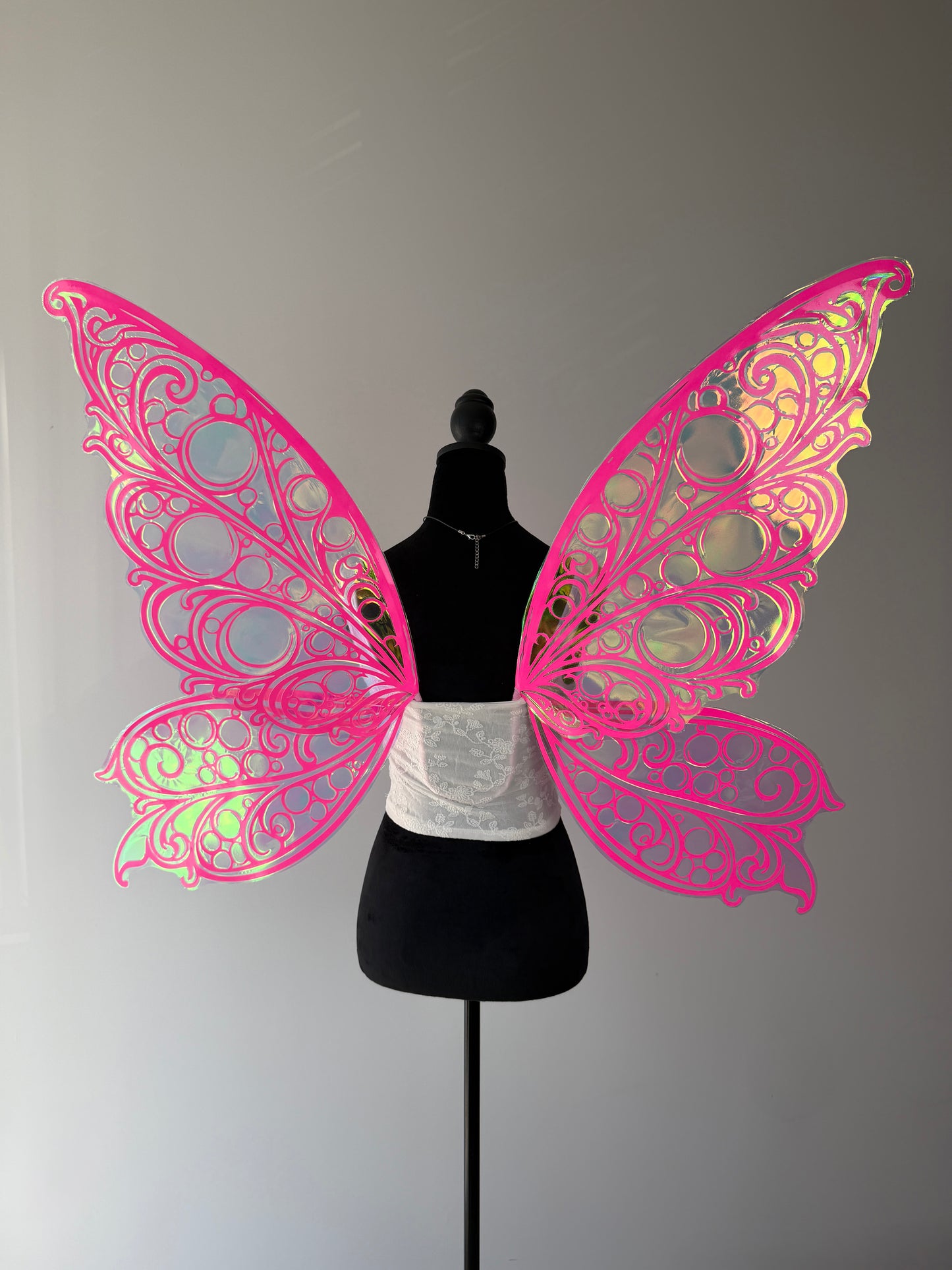 Pink butterfly wings on a mannequin against a gray background