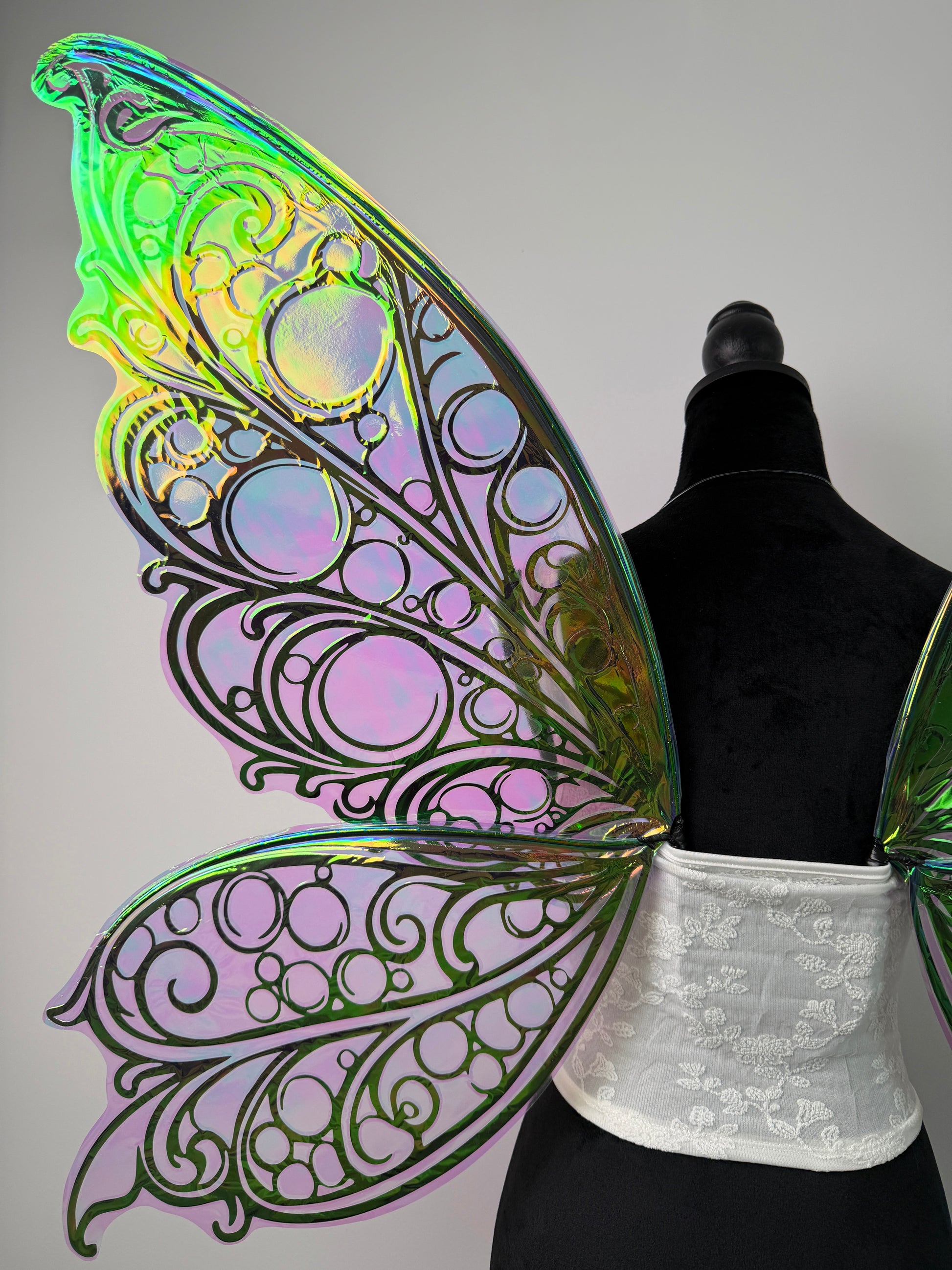 Iridescent butterfly wings on a mannequin against a gray background