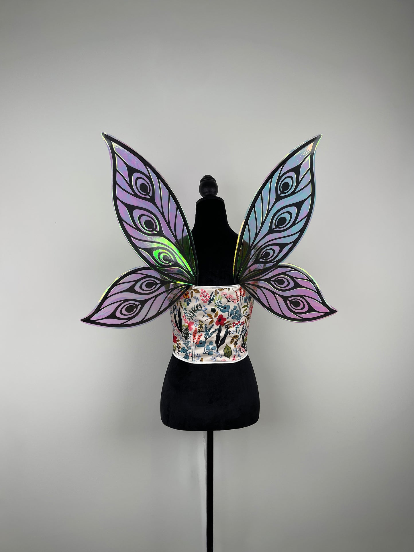 Mannequin wearing a colorful top with butterfly wings on a gray background