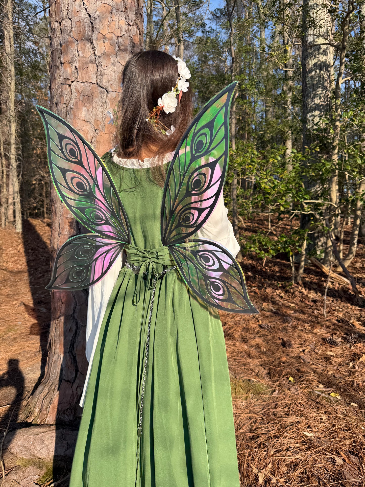 Person wearing a green dress and colorful fairy wings in a forest setting