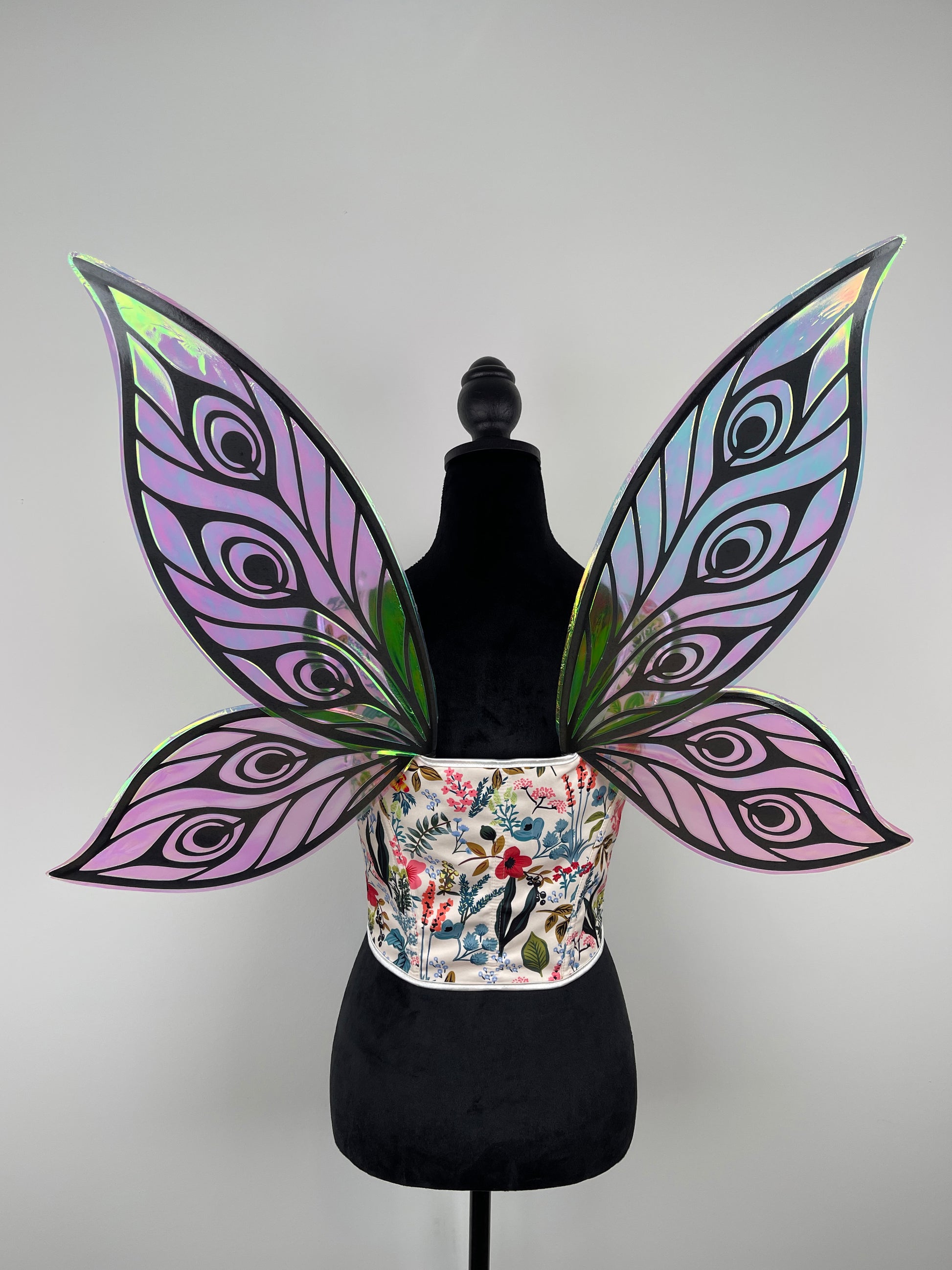 Butterfly wings on a mannequin with a floral-patterned corset against a gray background