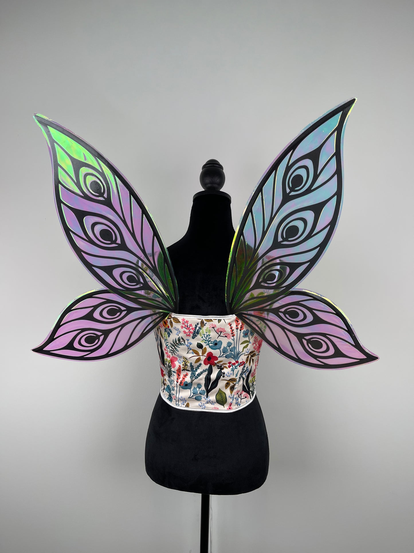 Butterfly wings with a colorful floral pattern on a mannequin against a gray background