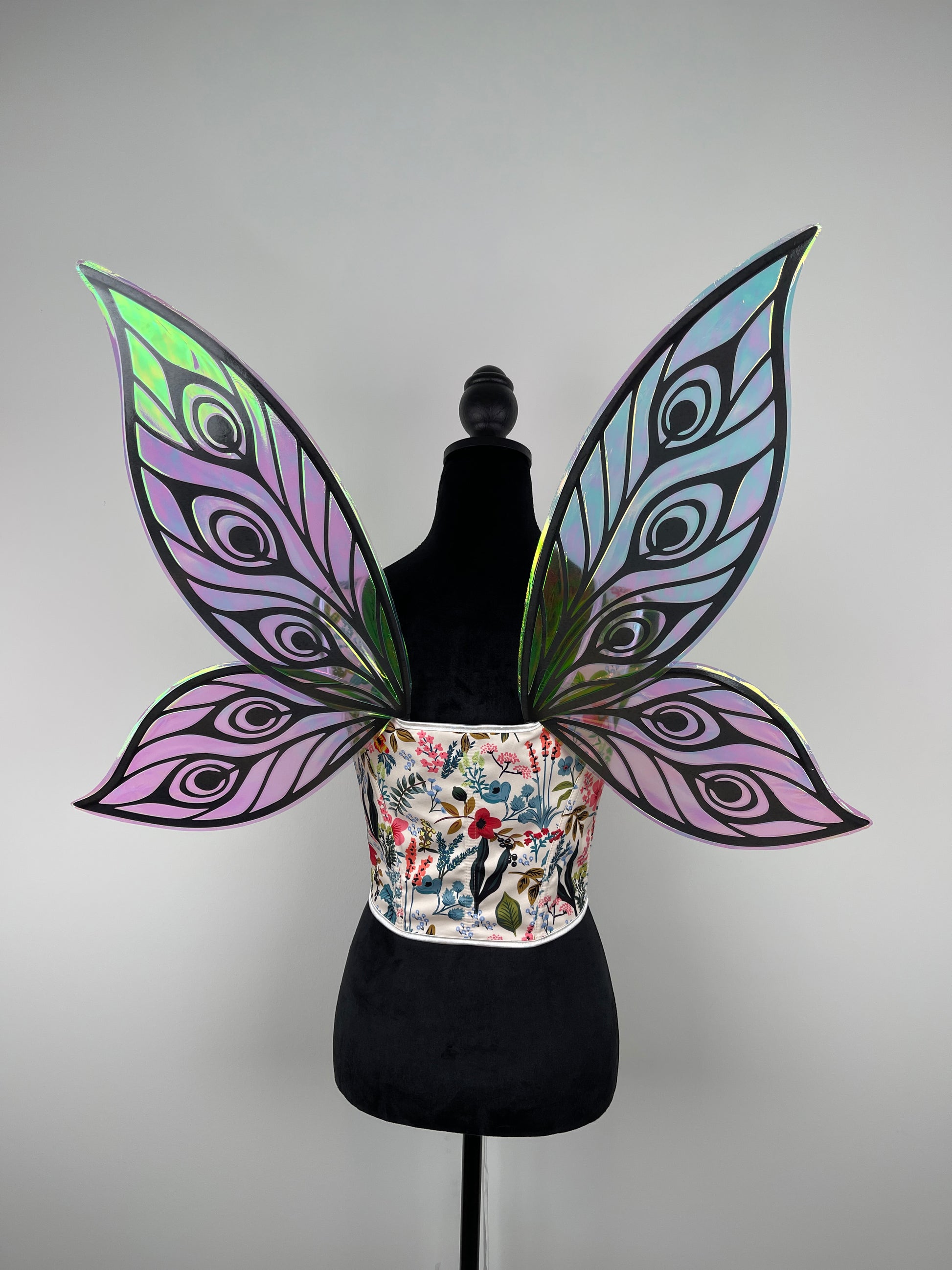 Butterfly wings with a colorful floral pattern on a mannequin against a gray background