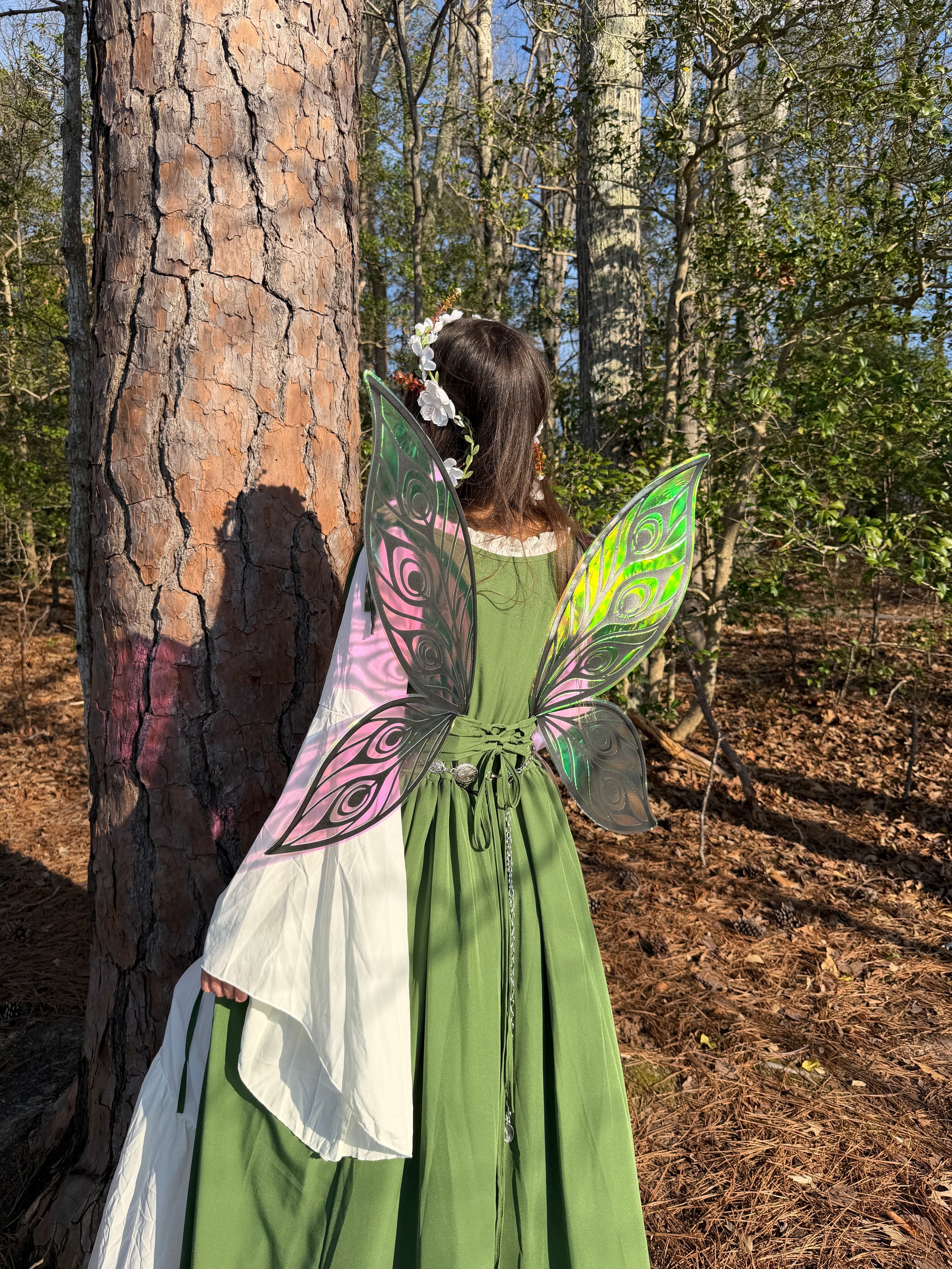 Person in a green dress with fairy wings standing in a forest