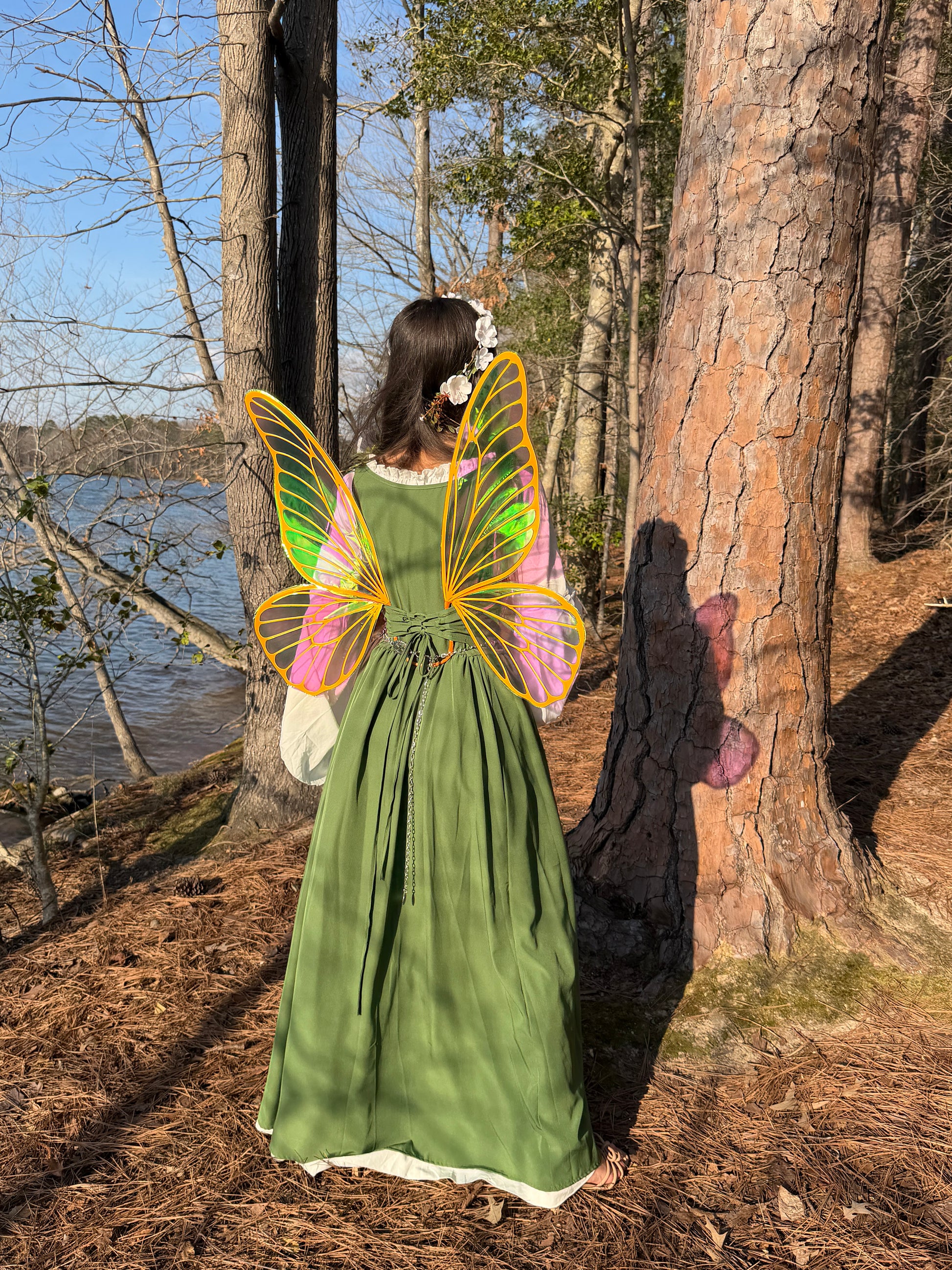Woman in woodland wearing translucent fairy wings with bright orange veins