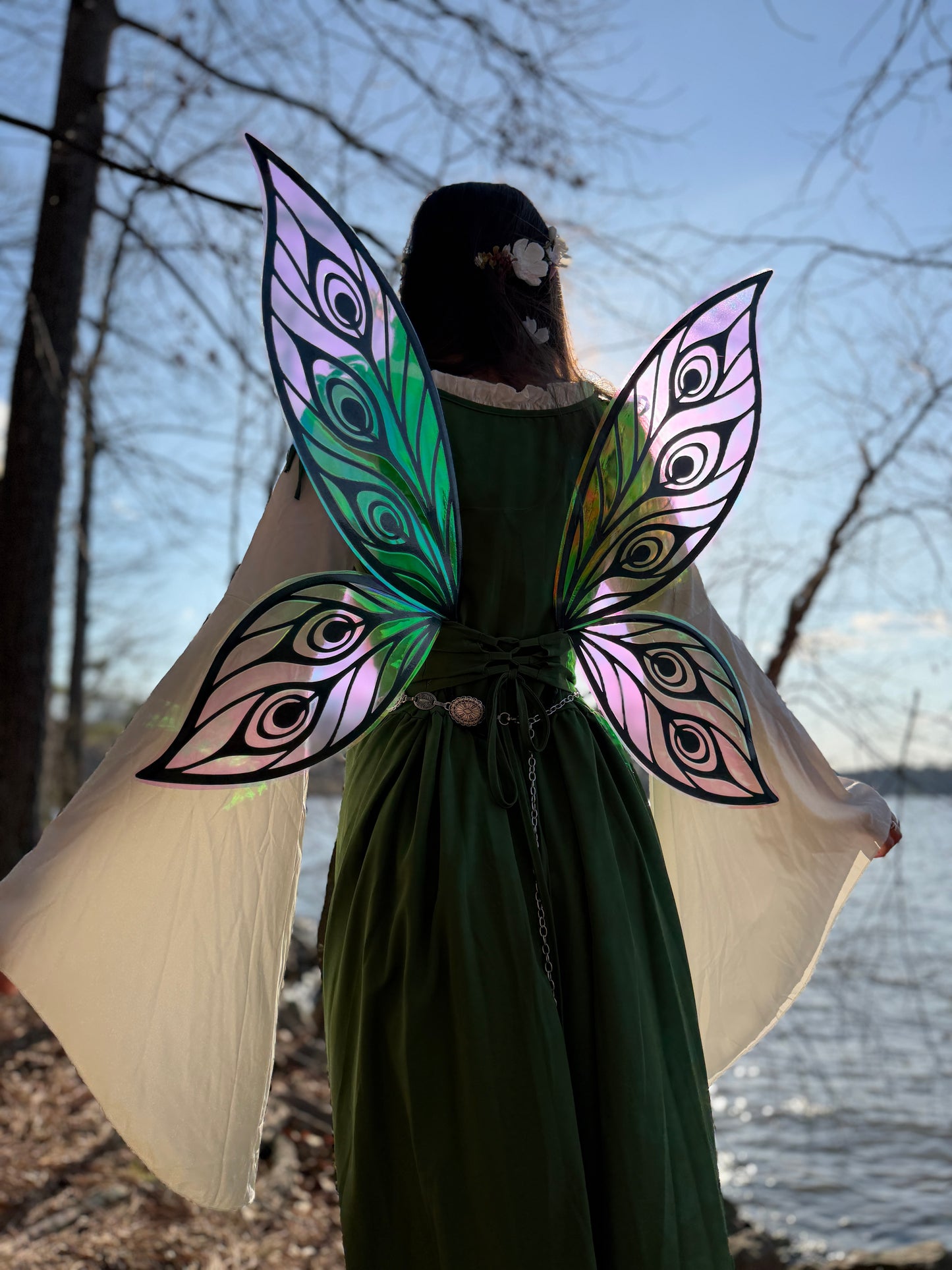 Person wearing a green dress with colorful butterfly wings against a natural background