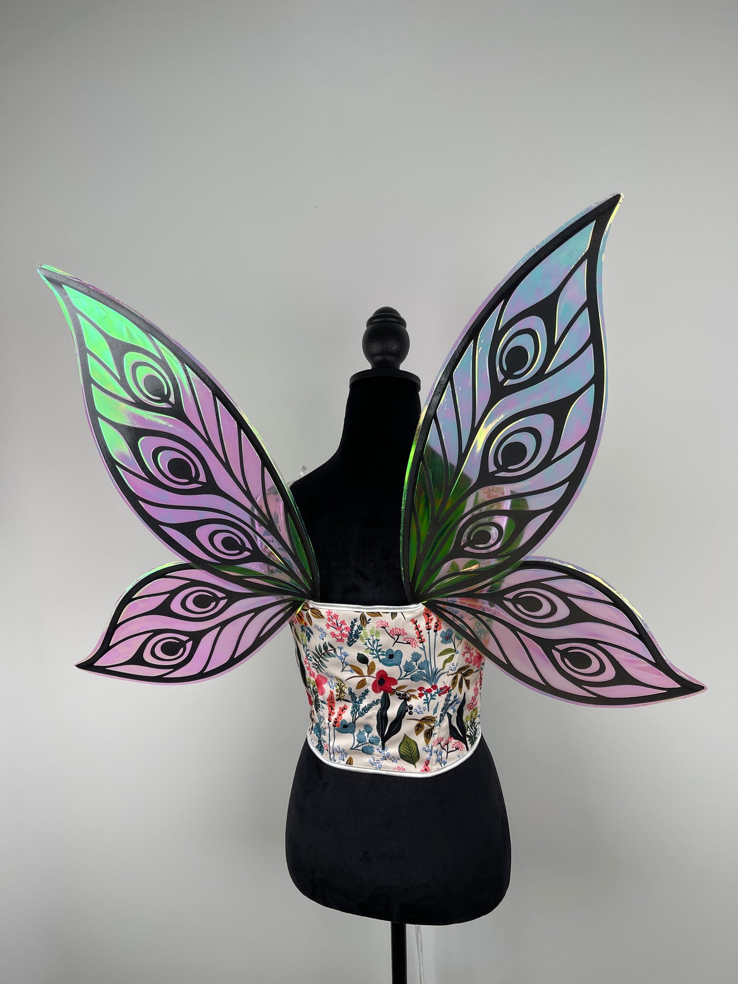 Butterfly wings with iridescent purple and green patterns on a mannequin against a gray background