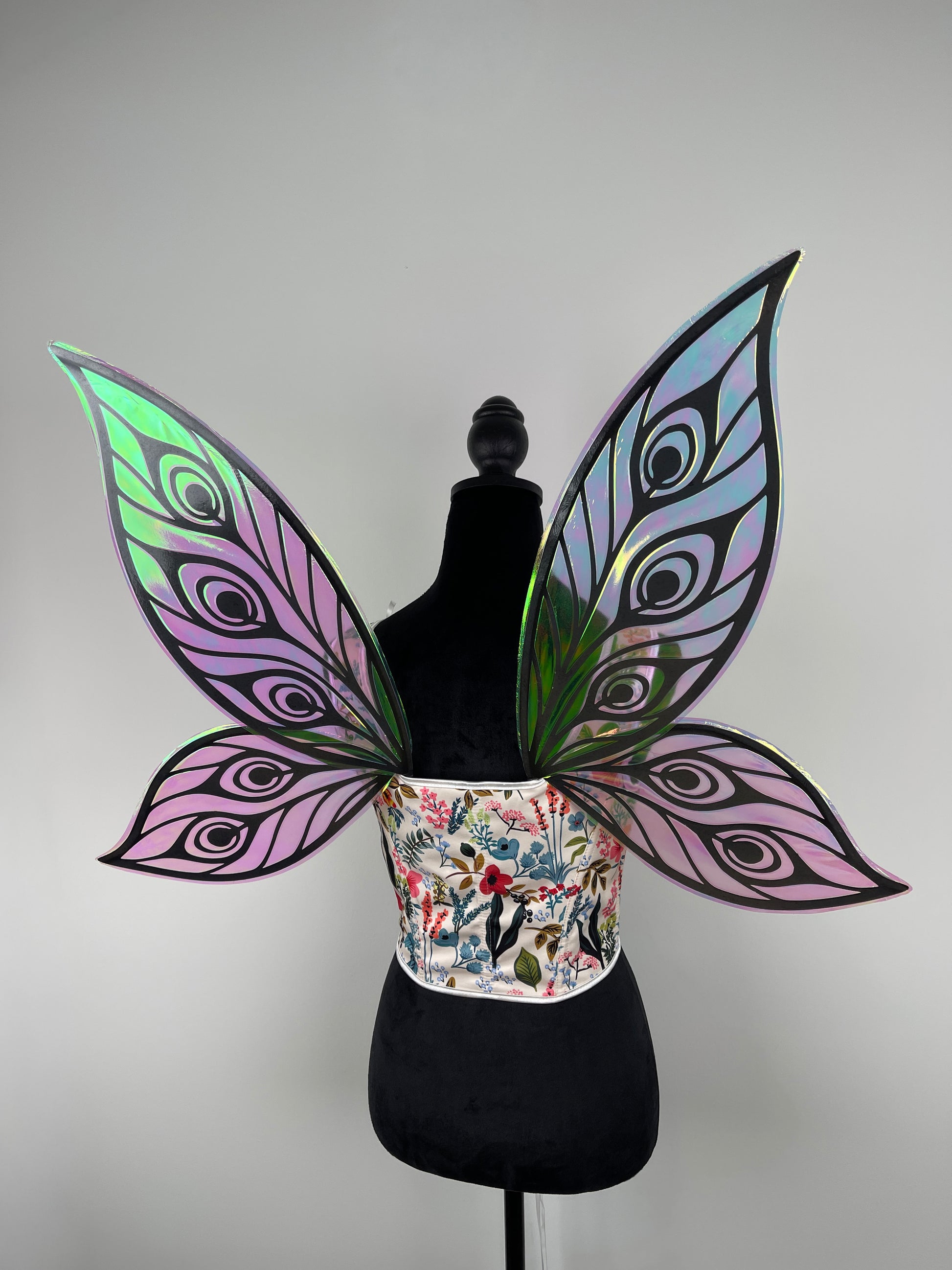 Butterfly wings with iridescent purple and green patterns on a mannequin against a gray background