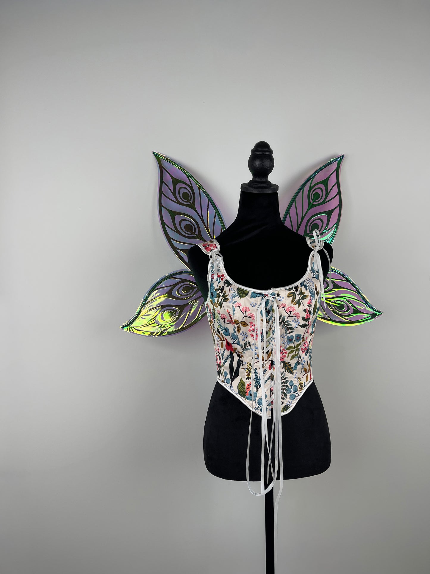 Decorative butterfly wing costume on a mannequin against a plain background