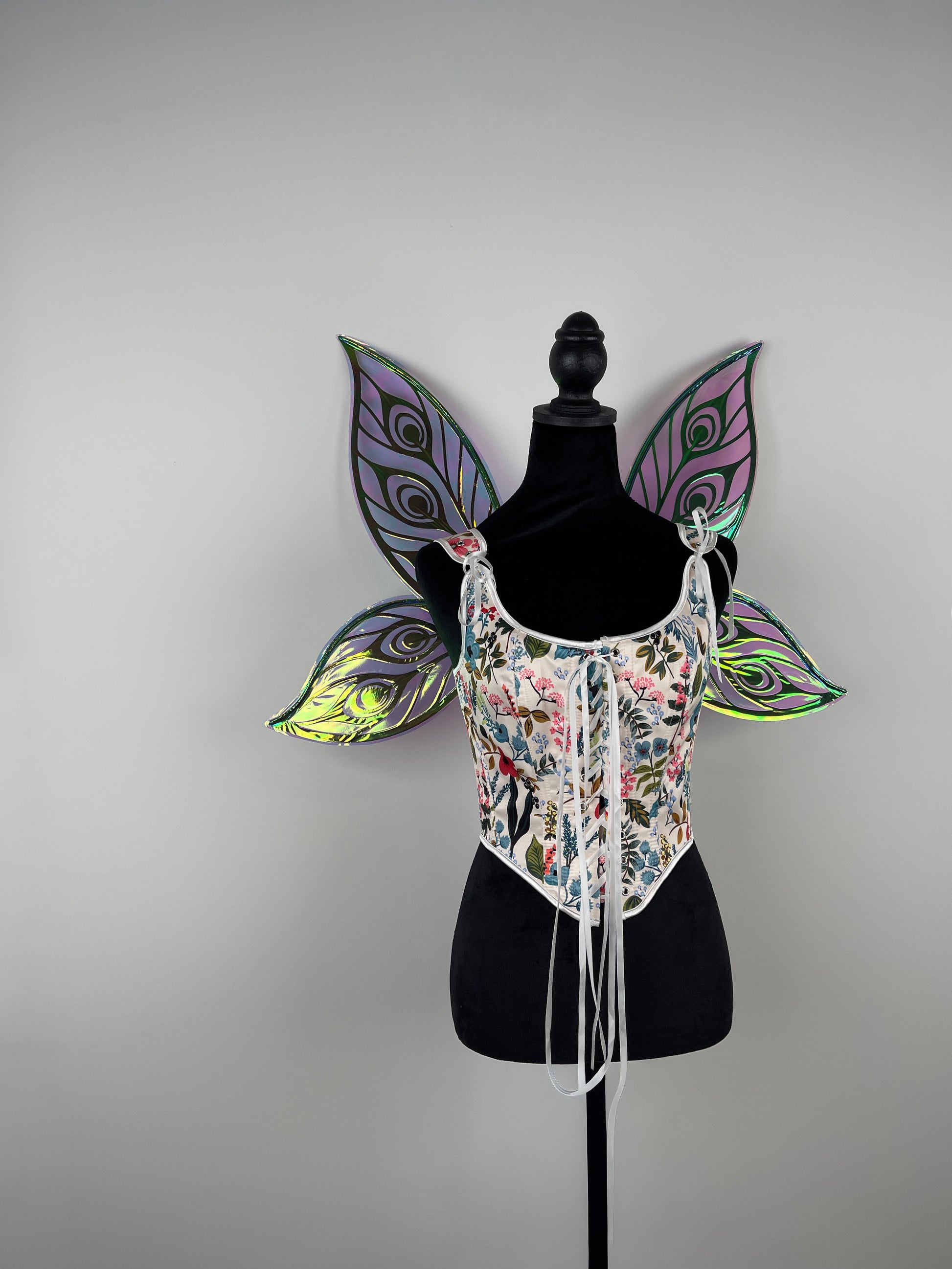 Decorative butterfly wing costume on a mannequin against a plain background