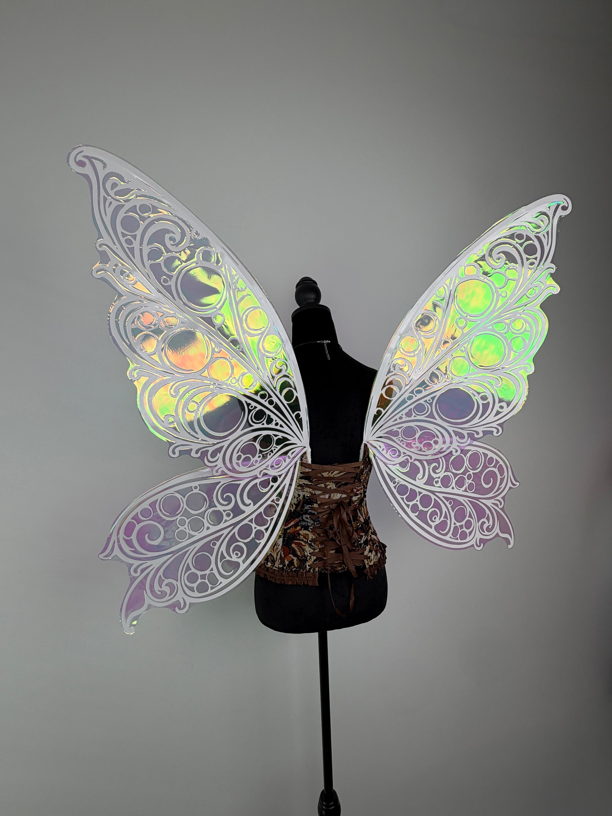 Butterfly wings with colorful patterns on a mannequin against a gray background