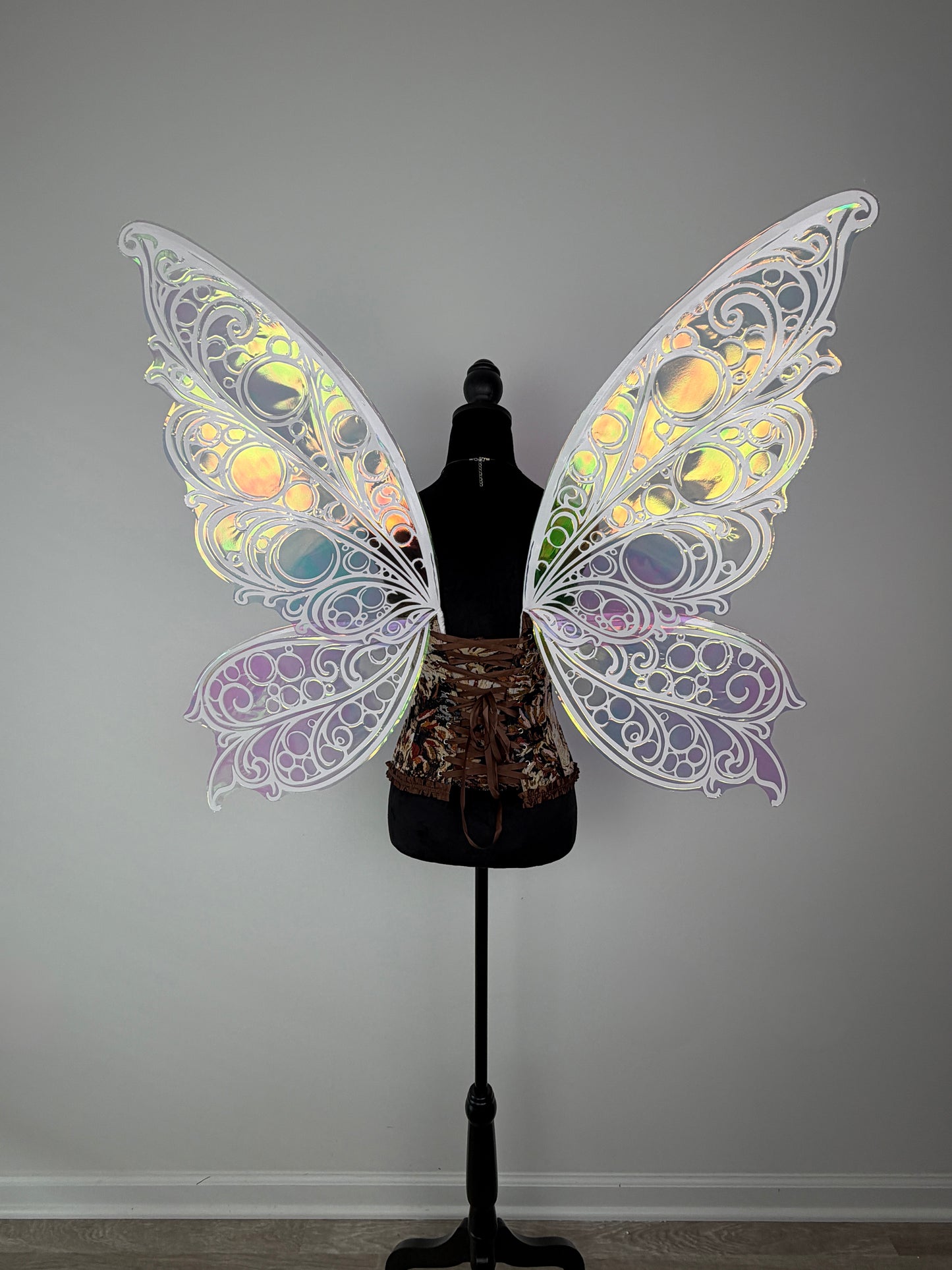 Decorative butterfly wings on a mannequin against a plain background