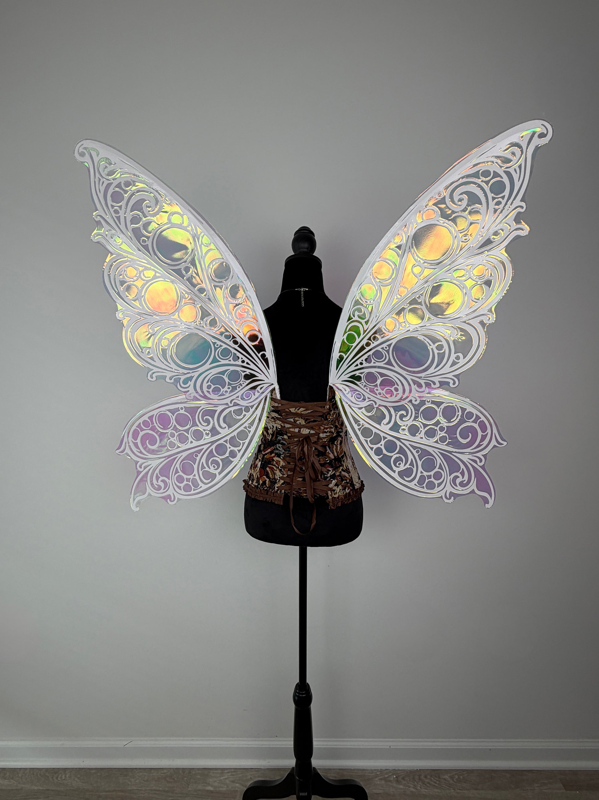 Decorative butterfly wings on a mannequin against a plain background