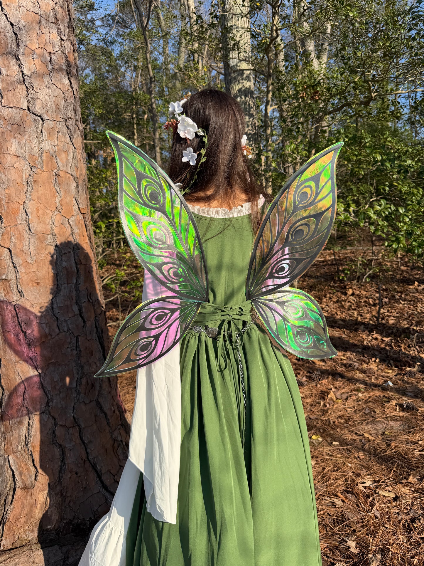 Person wearing green fairy costume with wings in a forest setting