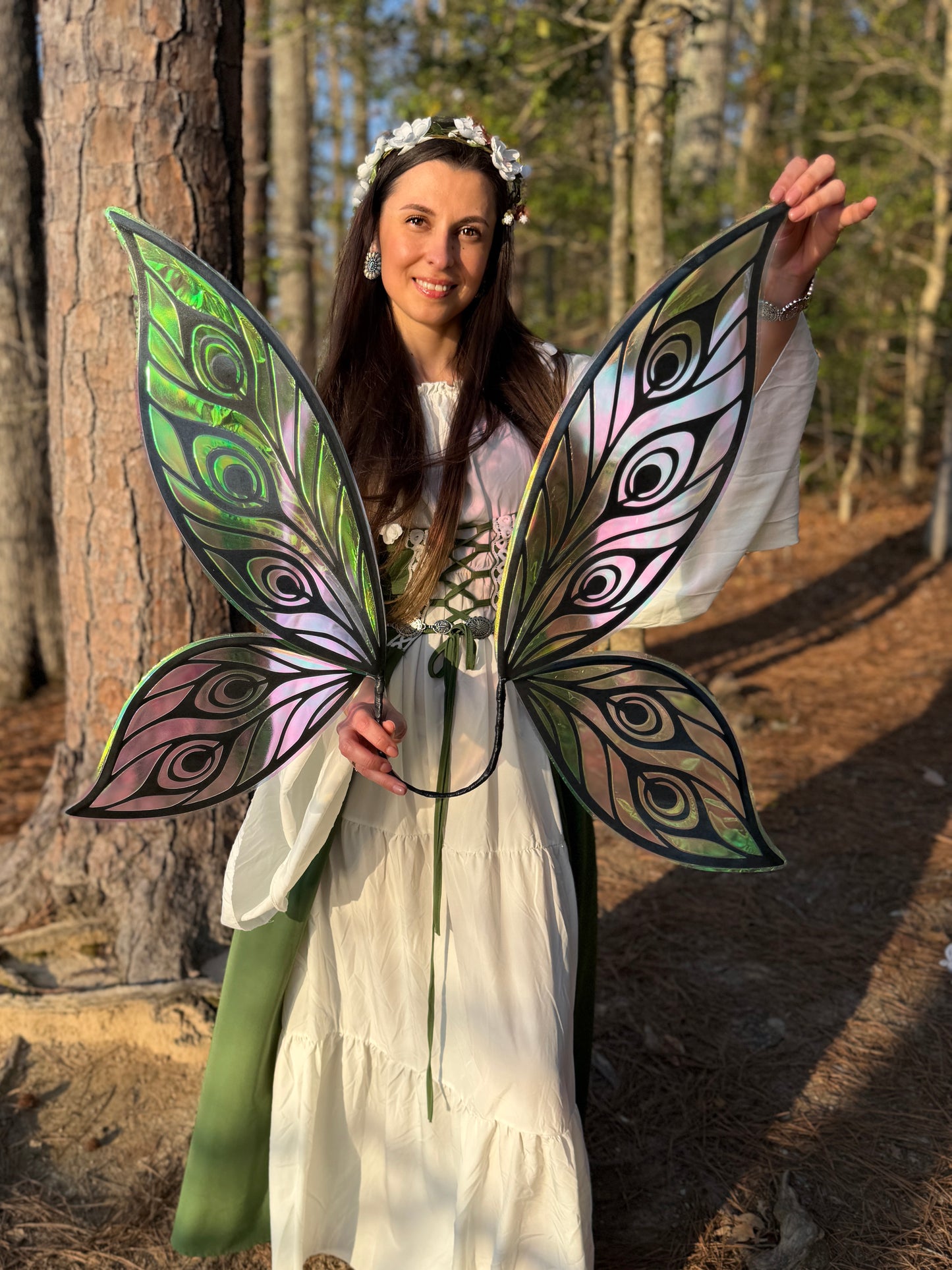 Woman in a forest setting wearing large, colorful butterfly wings.