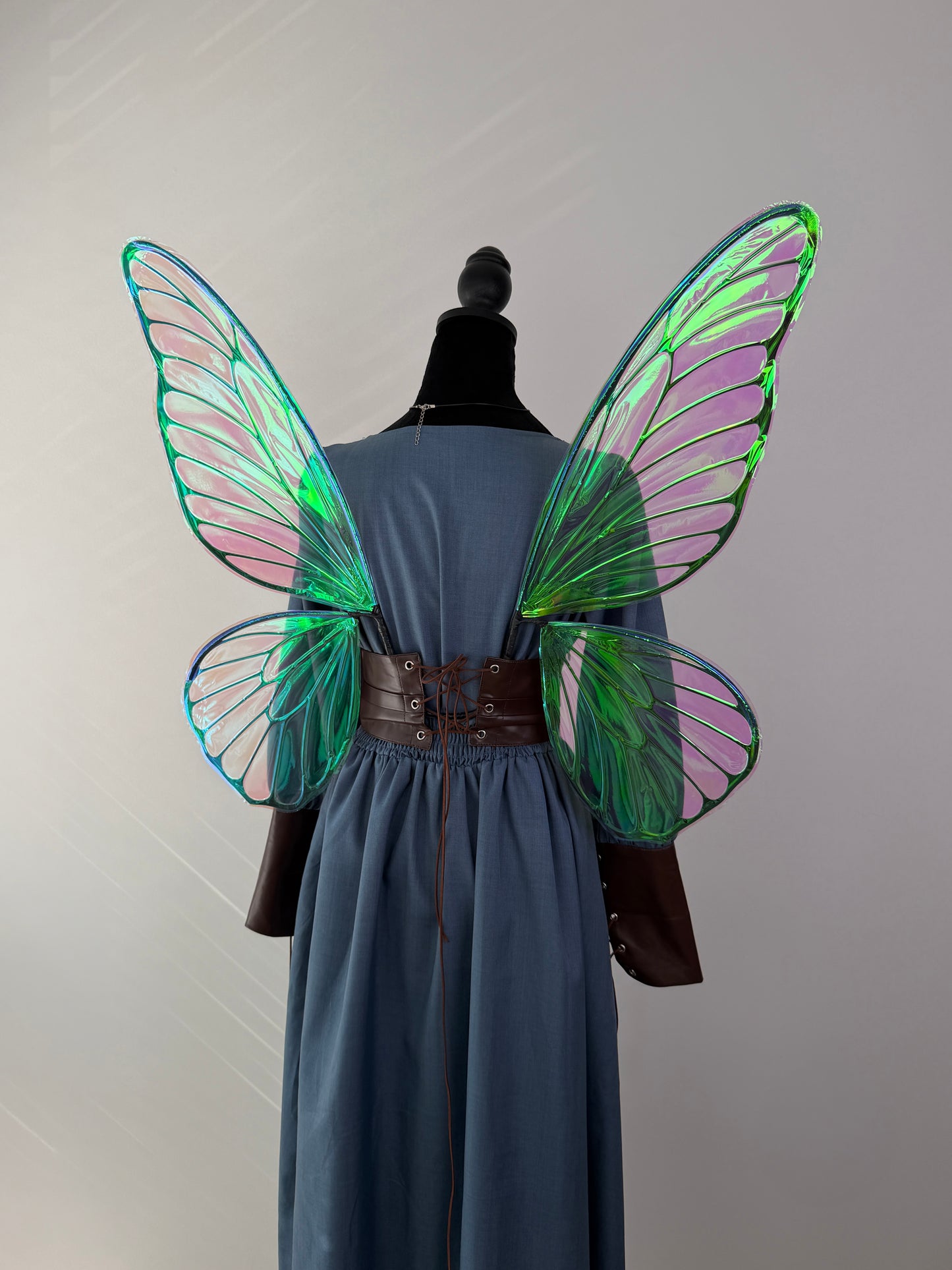 Handmade pink and green iridescent fairy wings shown from the back on a medieval dress.